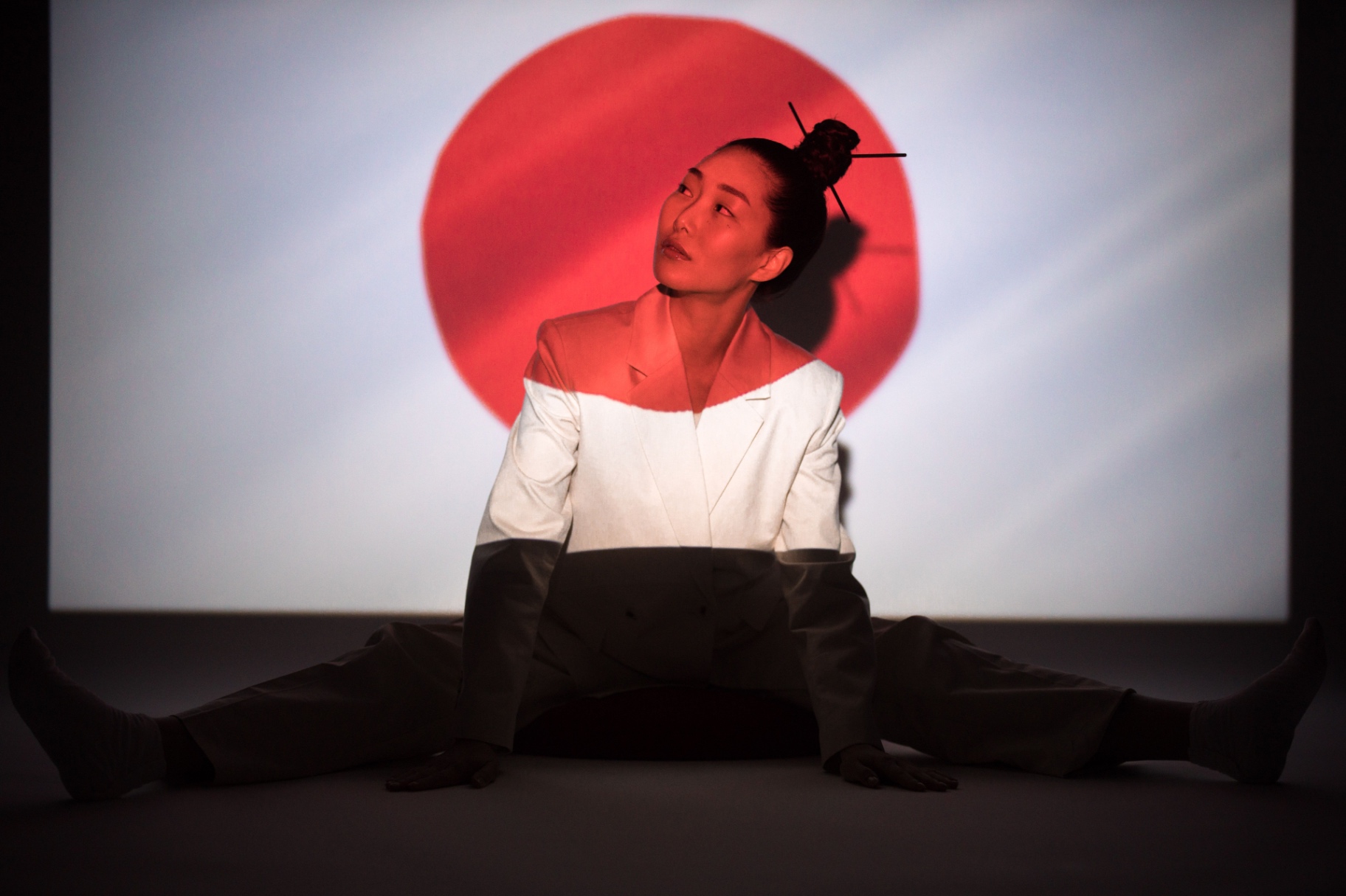 Model in a tailored white suit against a red sun backdrop