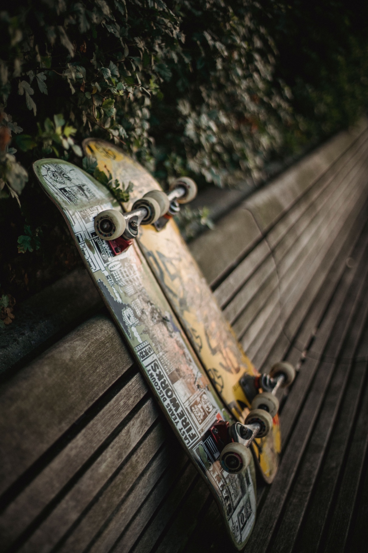 Two worn decks resting against a park bench at dusk