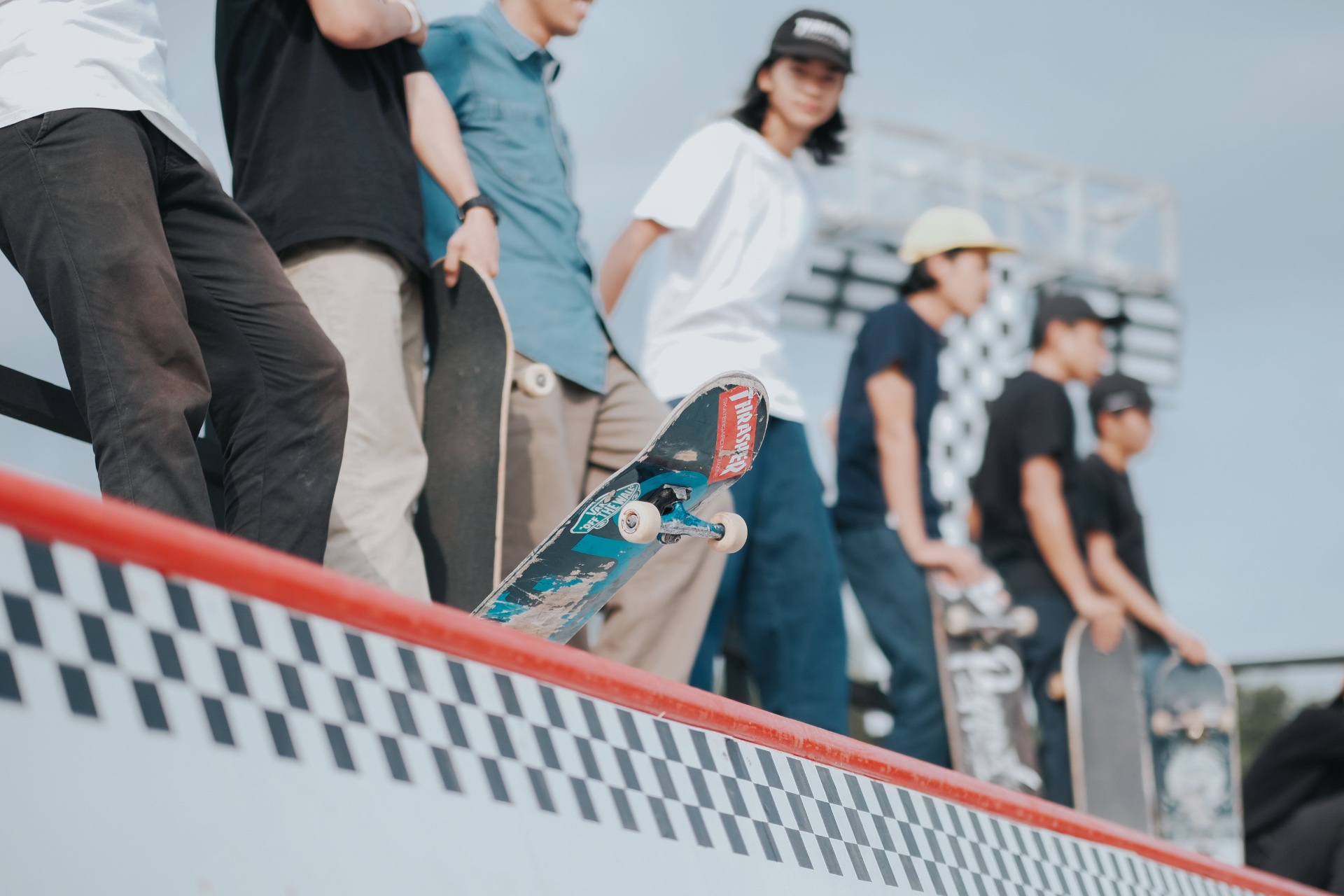 Line of skaters waiting at the top of a park ramp